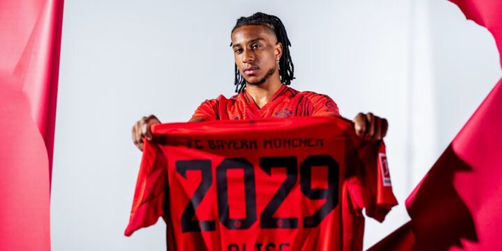 Michael Olise holding Bayern Munich's jersey during his unveiling