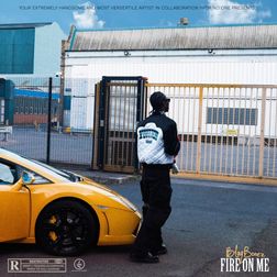 The cover art for Blaqbonez single Fire on Me features a stylish scene with Blaqbonez standing in front of a yellow sports car, parked near an industrial building with a fenced gate. He is wearing a black and white jacket, and his back is to the camera, adding a sense of mystery. The image combines urban and industrial elements, highlighting a gritty, street-inspired aesthetic.