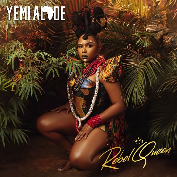 The Rebel Queen Album cover art image shows Yemi Alade in a lush tropical setting. She is dressed in a lush vibrant multi colored outfit with bold traditional African accessories include large beads and intricate hair styling. The album title Rebel Queen is prominently displayed in gold letttering at the bottom right corner with Yemi Alades name at the top left incorporating an African continent icon.